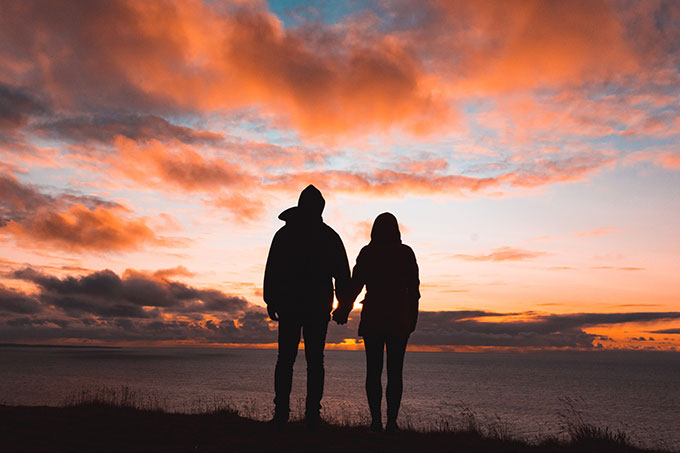 Couple holding hands looking into the sunset