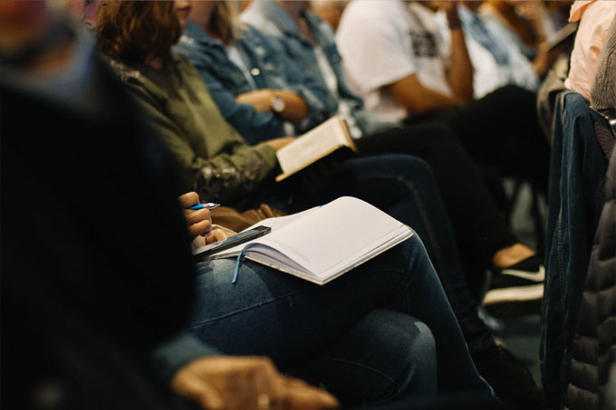 Group of people listening to a presentation and taking notes